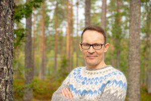 Kuvassa haastateltu kirjailija Timo Kyllönen taustanaan puita.