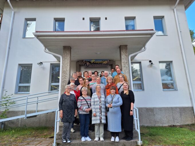 Kuvassa on joukko kuhmolaisia ja suomussalmelaisia yhdistystoimijoita sekä kuntien toimijoita kerääntyneenä Kumppanuustalon portaille ryhmäkuvaan. 